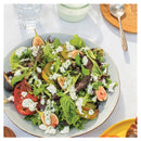 Salad with figs, tomatoes, and feta cheese on a white table.